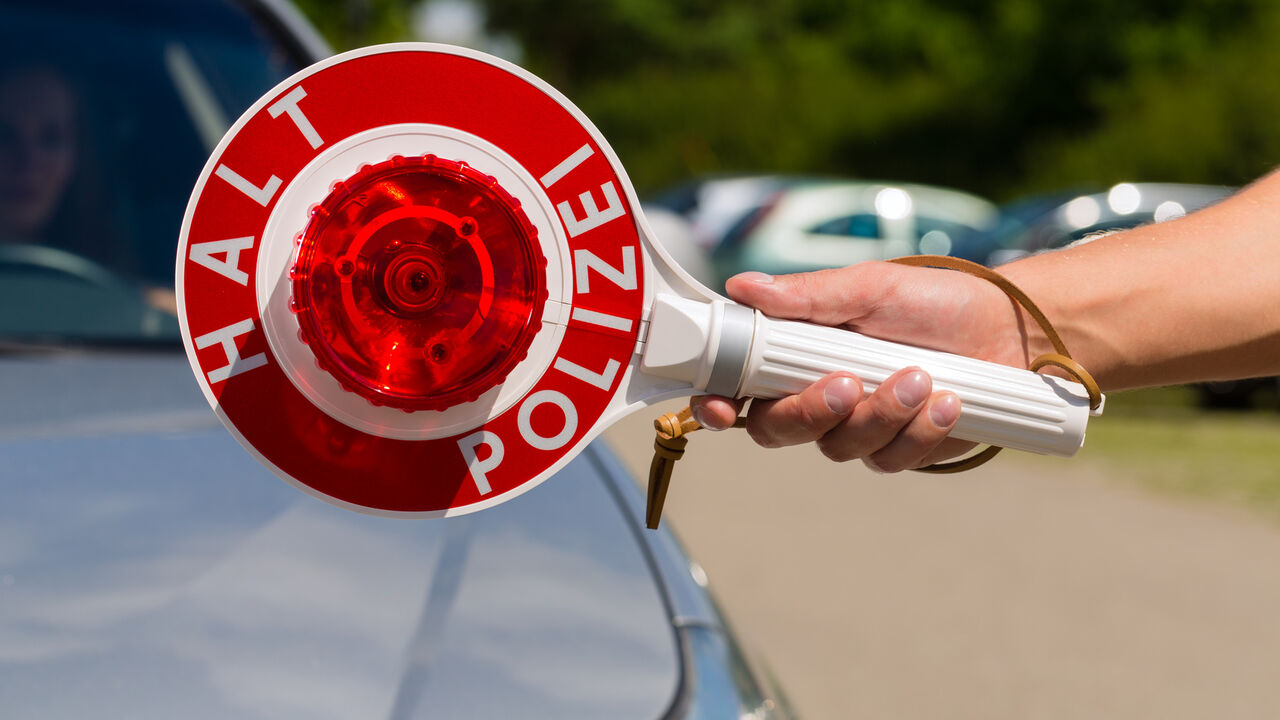 Polizeikontrolle mit Halt Polizei-Schild im Vordergrund