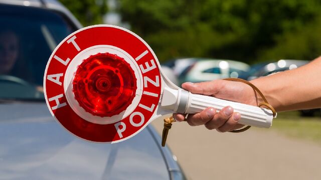 Polizeikontrolle mit Halt Polizei-Schild im Vordergrund